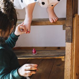 close-up-girl-applying-nail-polish-her-sister-s-toe-nail-home